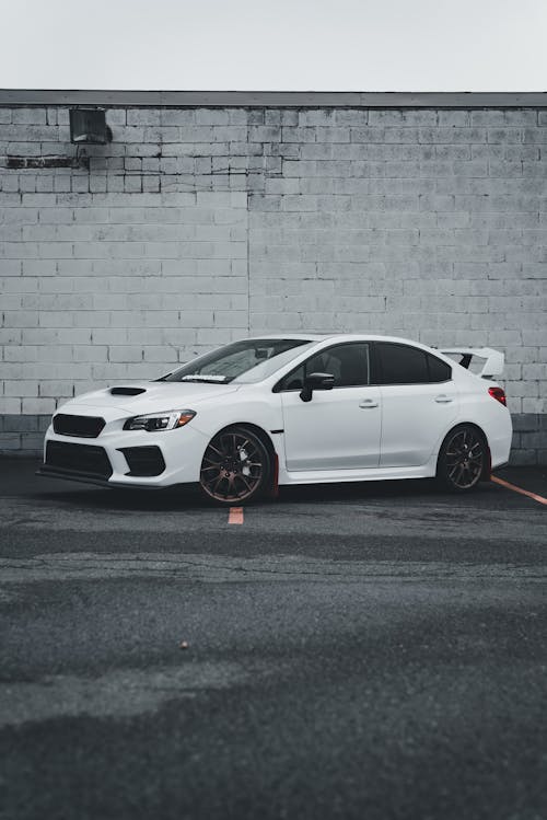 A white subaruna parked in front of a brick wall