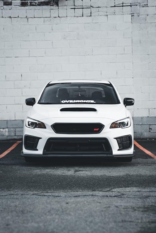 A white subaruna parked in front of a white wall