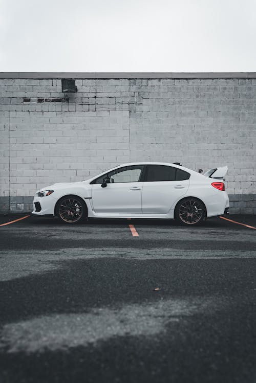 A white car parked in front of a white wall