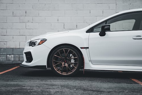 The front end of a white subaruna with red rims