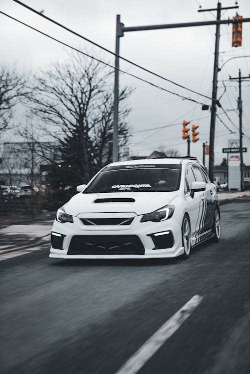 A white subaruna driving down the road