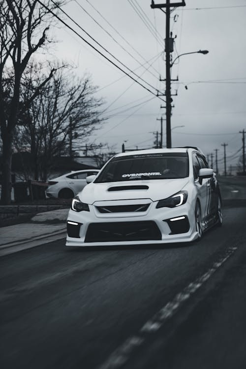 A white car driving down a street