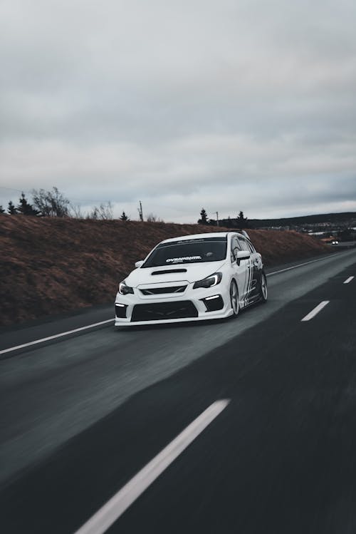 A white car driving down a road