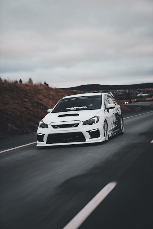 A white car driving down a road