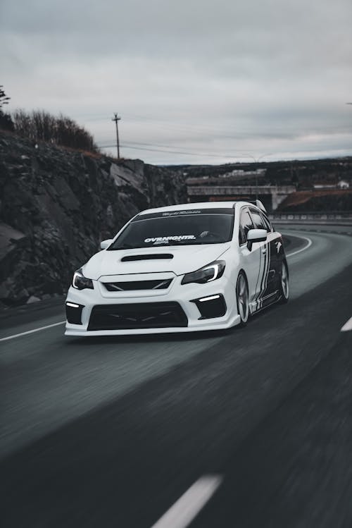 A white subaruna driving down a road