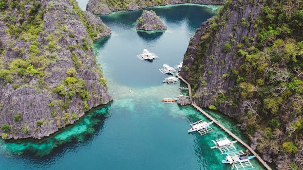 Stunning aerial shot of boats in crystal clear waters surrounded by rocky cliffs in Coron, Philippines.