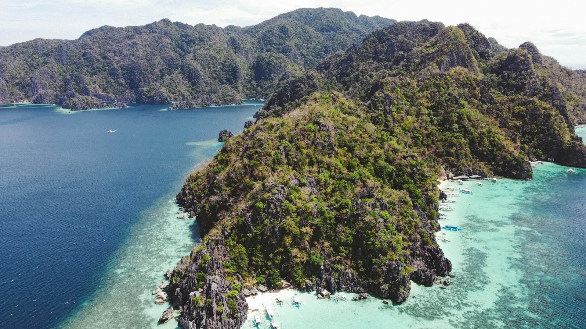 Discover the breathtaking aerial view of Coron with lush hills and vibrant blue waters in the Philippines.
