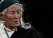 一位穿着传统服装的老妇人，在特写肖像中看起来若有所思