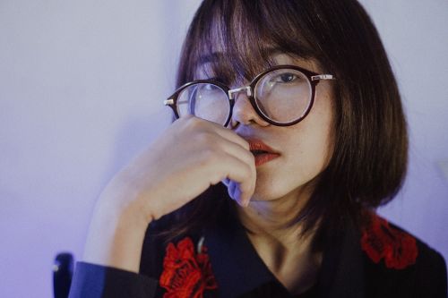 Free Close-up portrait of a stylish woman wearing large eyeglasses posing against a soft background. Stock Photo
