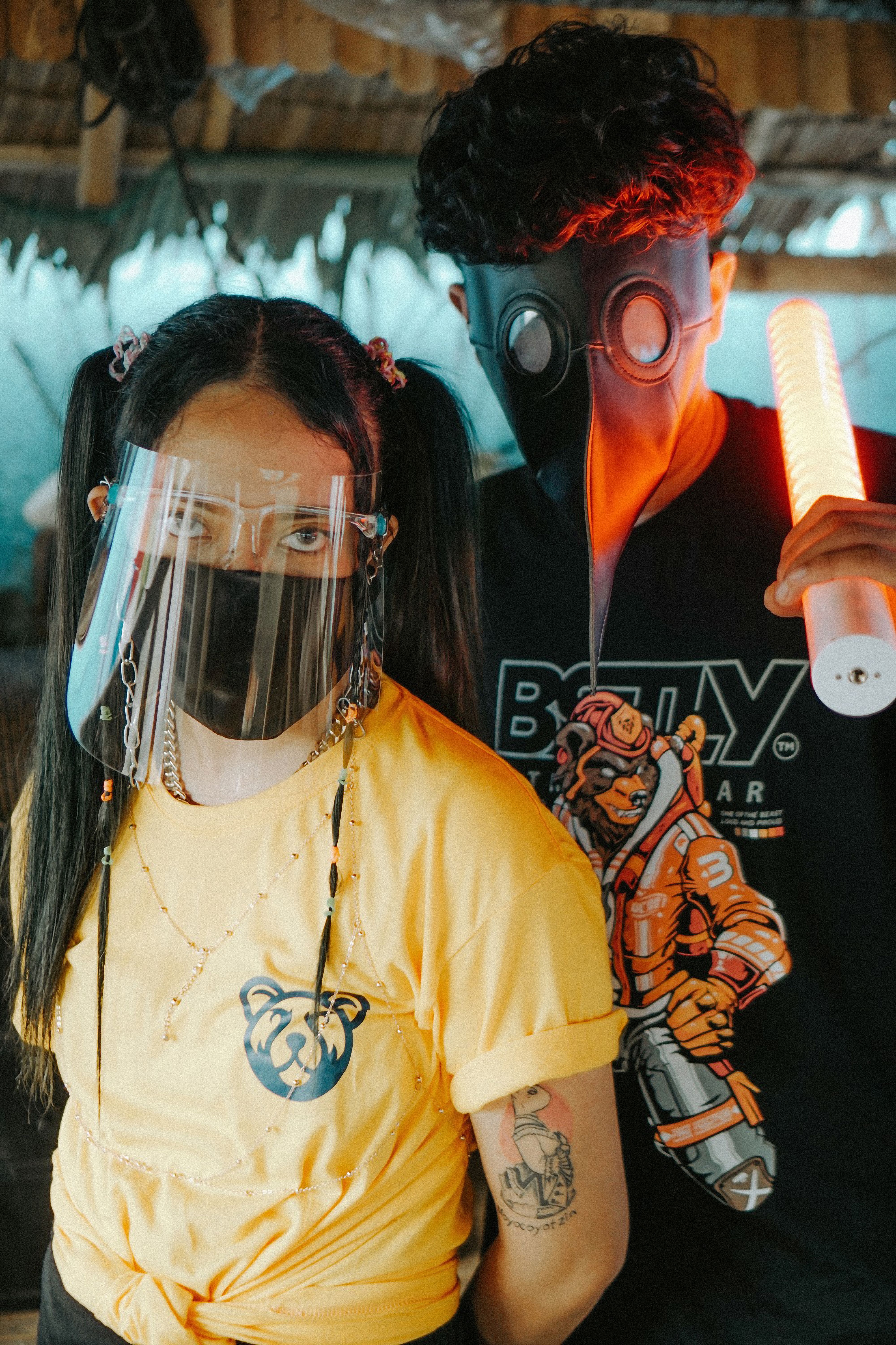 Two young adults wearing face mask and shield with futuristic vibe indoors.