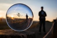 透过玻璃球体捕捉到的日落令人惊叹，倒映出站立的轮廓