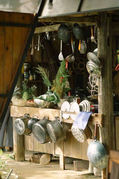 Free A cozy wooden kitchen with vintage pots and fresh herbs displayed outdoors, creating a rustic atmosphere. Stock Photo