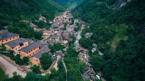 Free Aerial view of a picturesque village nestled in a lush valley in Jiangxi, China, surrounded by greenery. Stock Photo