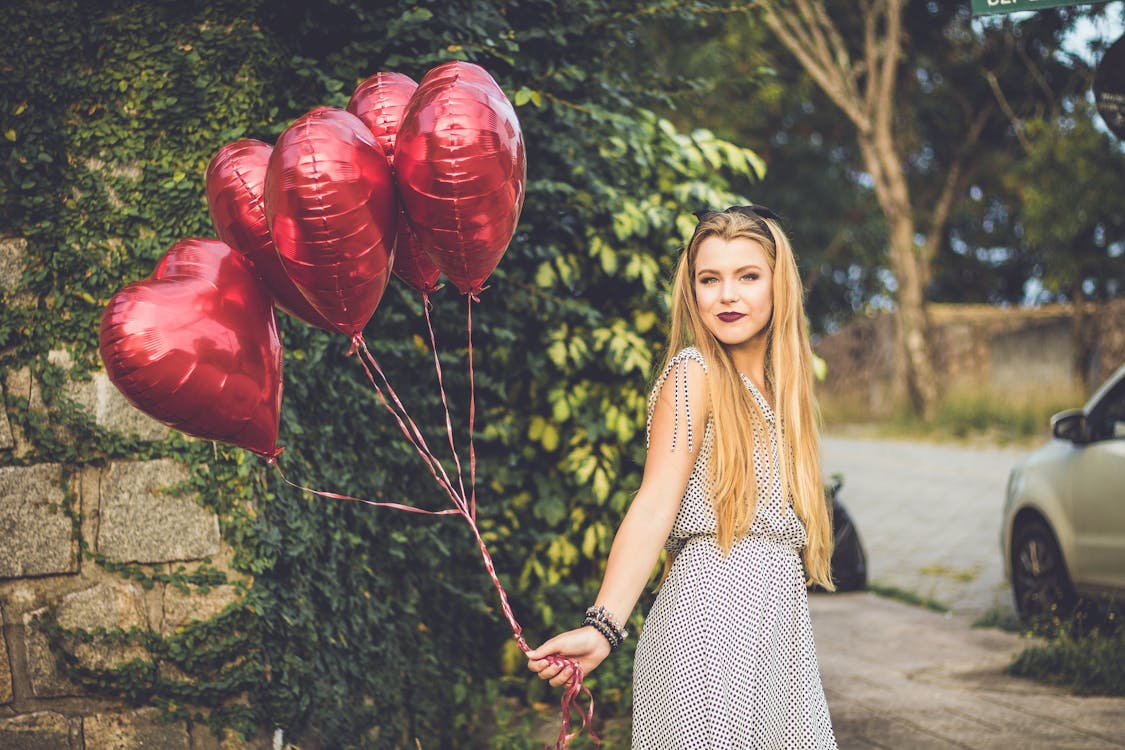 Free Woman Wearing Grey Dress Holding Heart Balloons Stock Photo