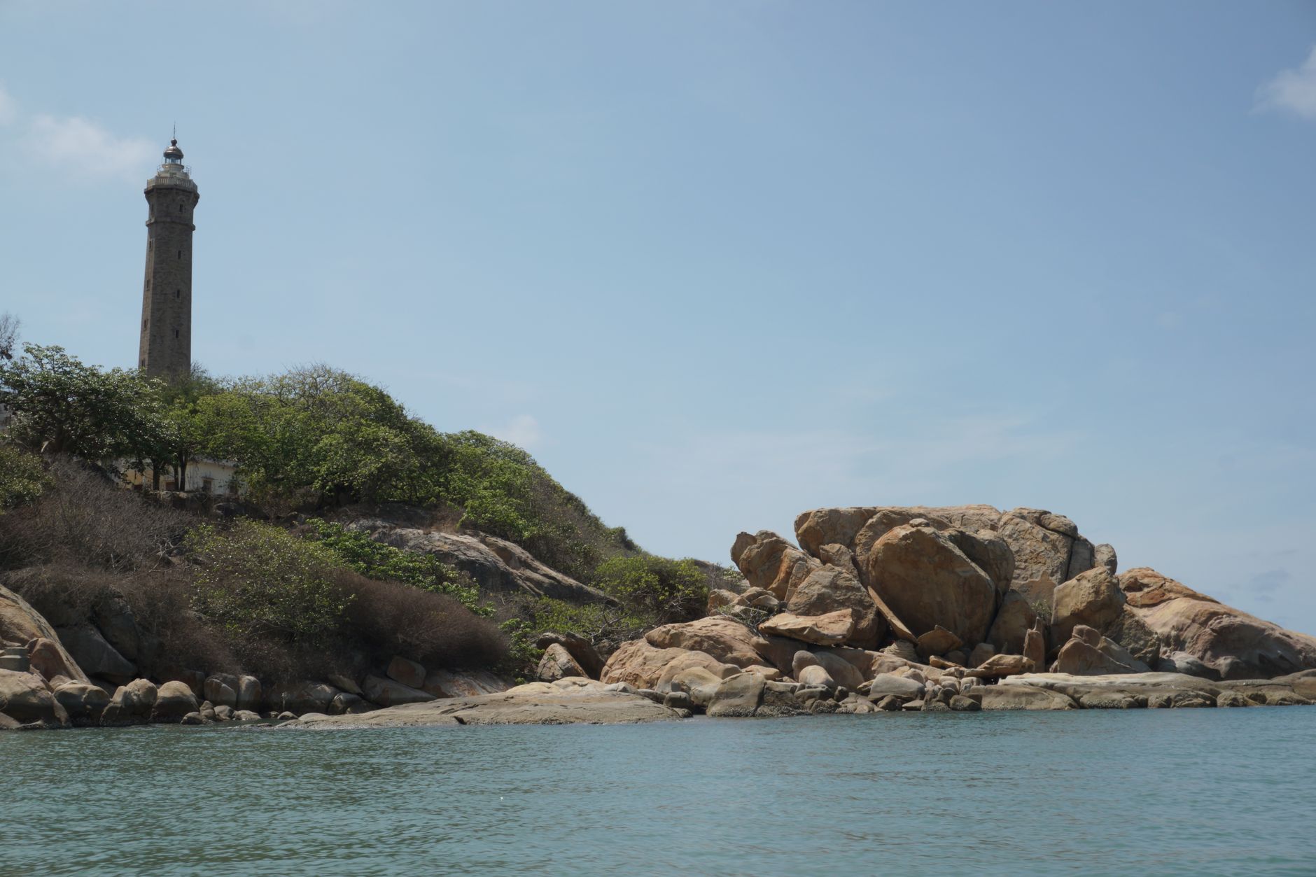 Picturesque view of Ke Ga Cape lighthouse against a serene seascape with rocky shore.