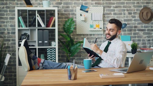 A man is sitting at his desk and reading a book