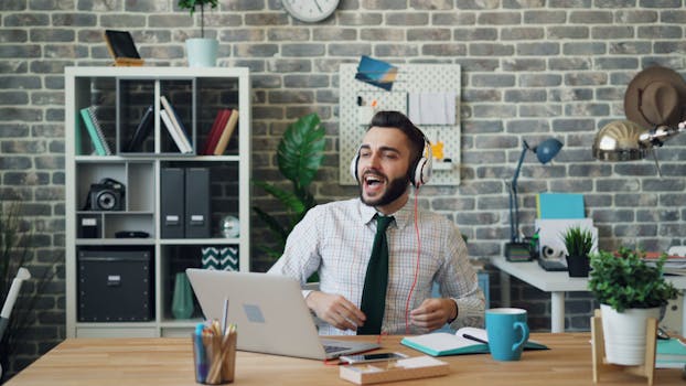 Smiling man with headphones enjoying music at his office desk.