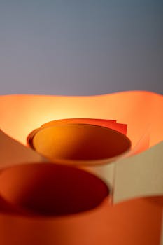 Close-up of rolled paper with orange lighting, creating an abstract and modern art piece.