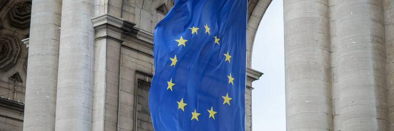 European Union flag fluttering beneath the Cinquantenaire Arch in Brussels, Belgium.