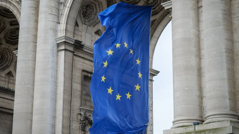 European Union flag fluttering beneath the Cinquantenaire Arch in Brussels, Belgium.