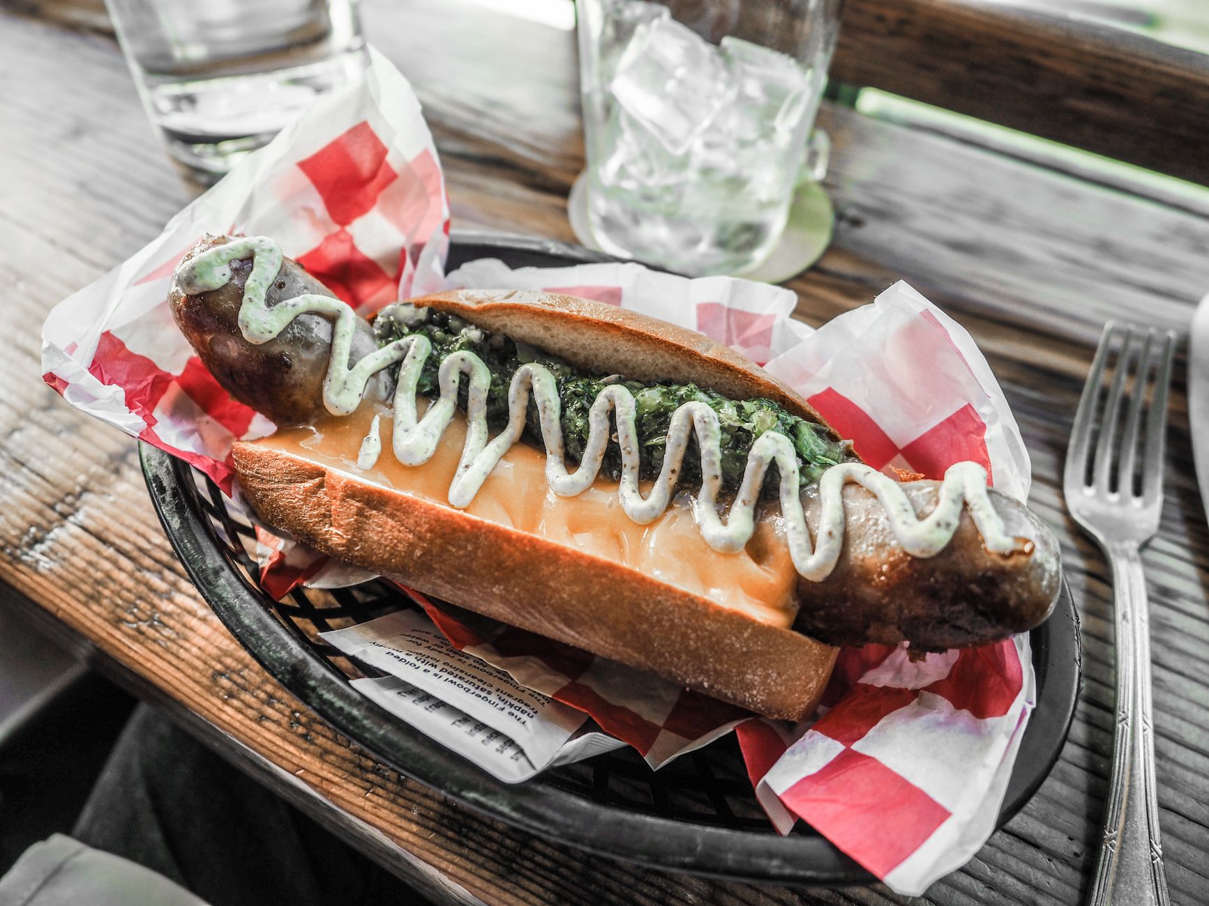Delicious sausage sandwich topped with green sauce, perfect for a flavorful meal.