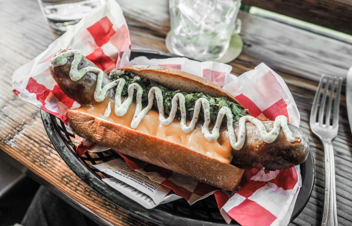 Delicious sausage sandwich topped with green sauce, perfect for a flavorful meal.
