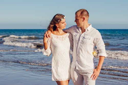 Free Couple Looking at Each Other Beside Beach Stock Photo