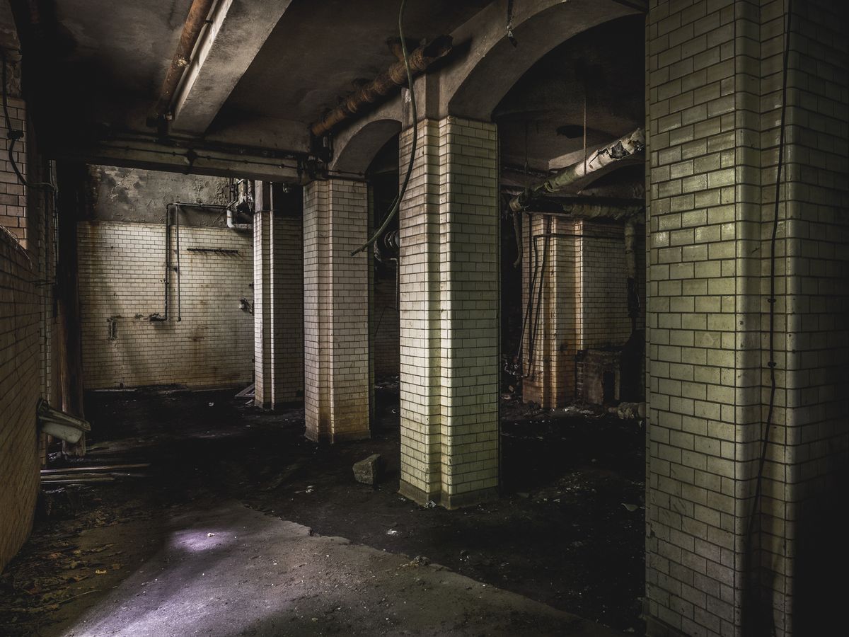 Explore the eerie atmosphere of this dark, abandoned building with arches. Stock Photo.