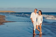 一对夫妇在阳光明媚的海滩上，面朝大海，浪漫地散步