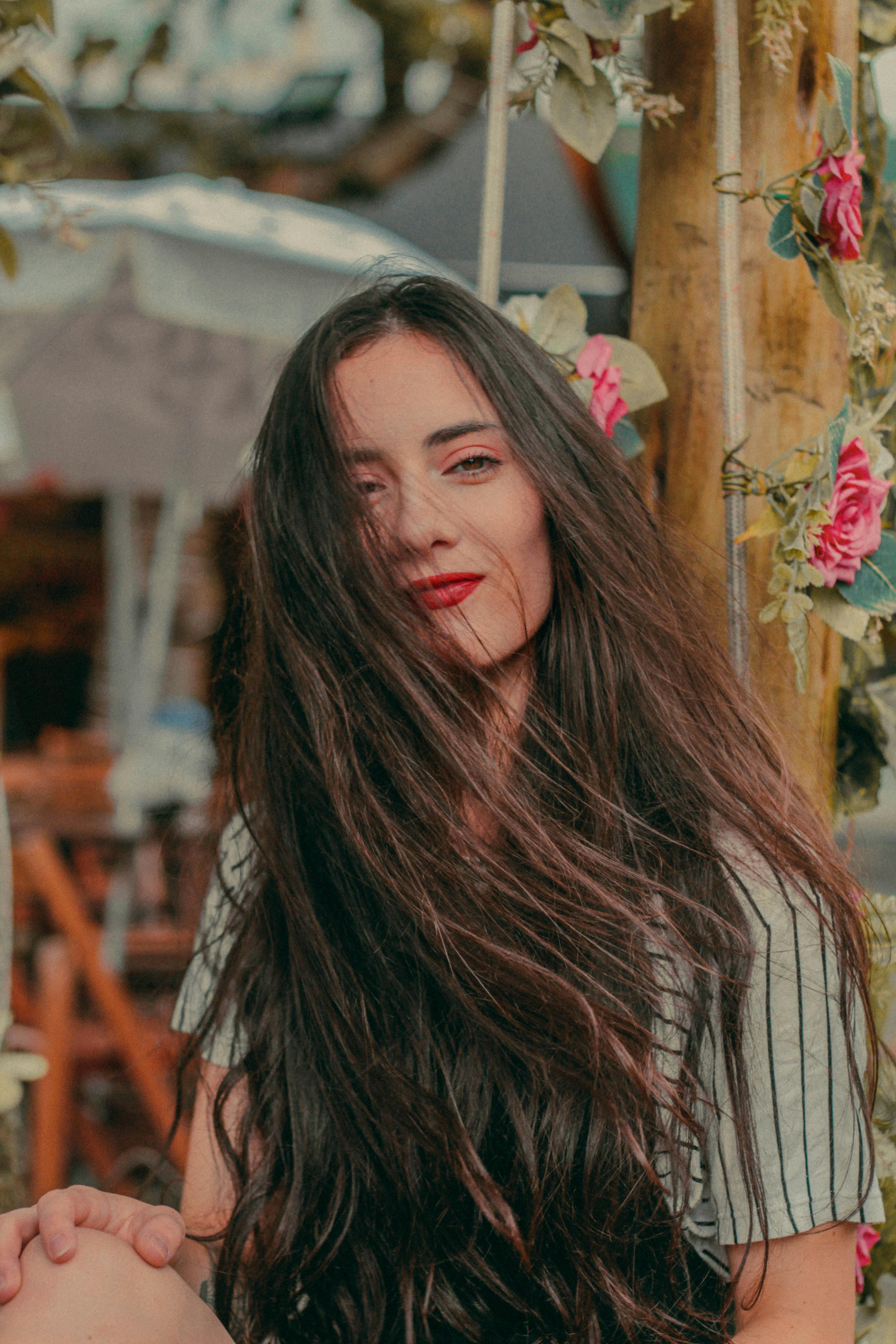 一位长发年轻女子在花卉背景的户外摆姿势