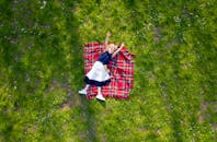 在阳光明媚的户外，快乐的孩子躺在草地上的格子毯子上