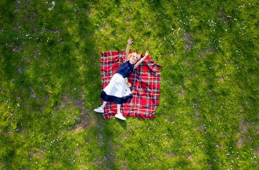 在阳光明媚的户外，快乐的孩子躺在草地上的格子毯子上