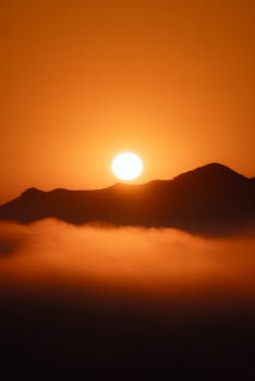Golden sunset casting a warm glow over misty mountains creating a tranquil silhouette.