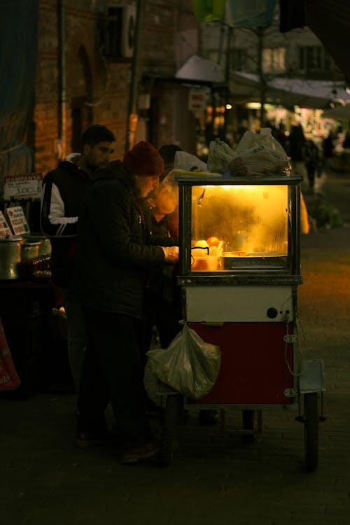 A man and woman are standing in front of a food cart