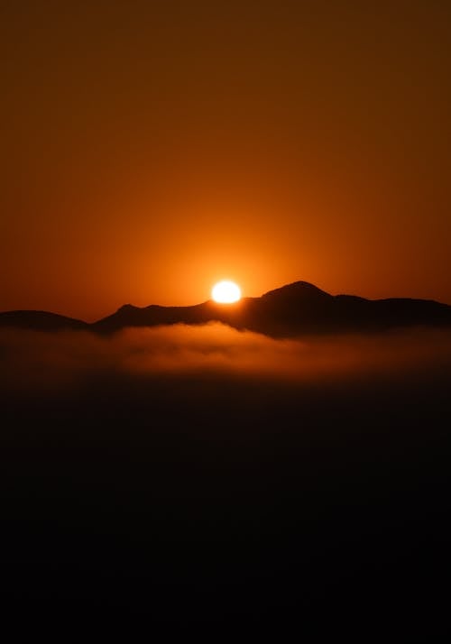 The sun rises over the mountains with fog