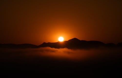 The sun rises over the mountains with fog