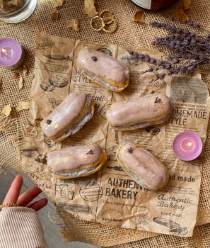 Elegant lavender eclairs on vintage paper with candles and rustic decor.