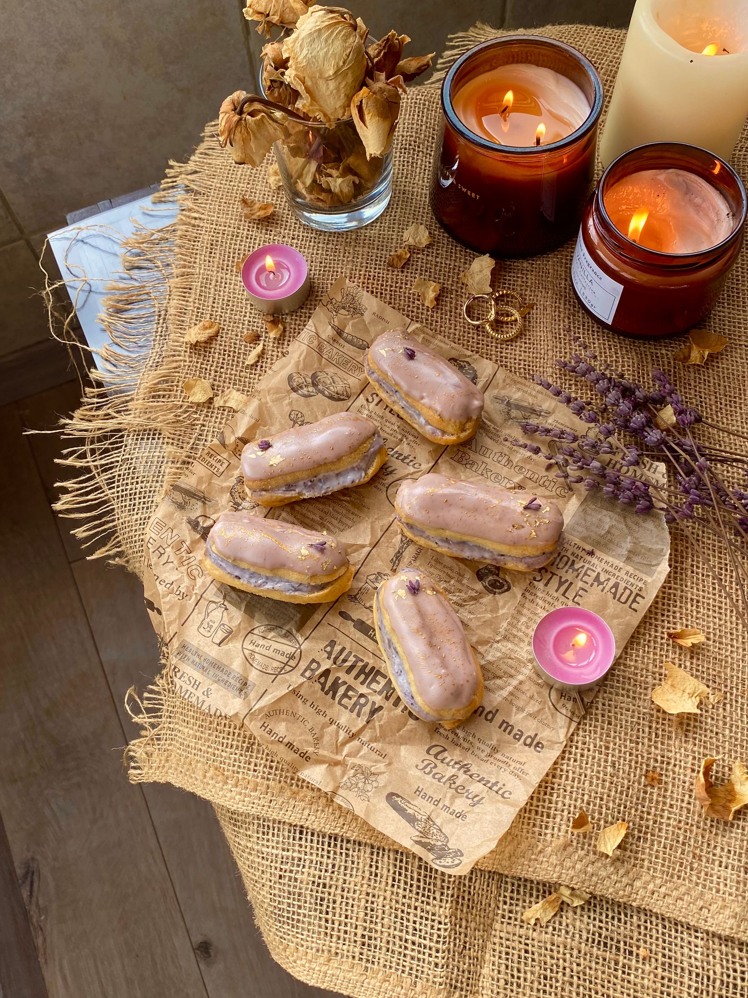 Lavender eclairs on a rustic table setting with candles, creating a cozy atmosphere.