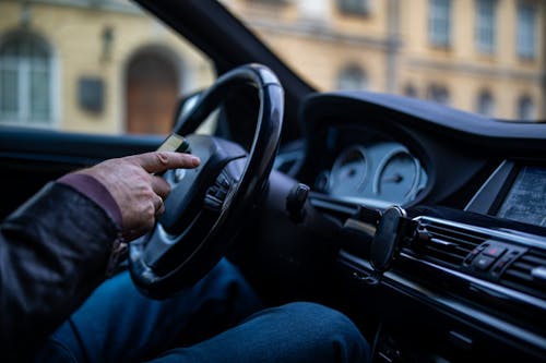 A man is driving a car with his hands on the steering wheel