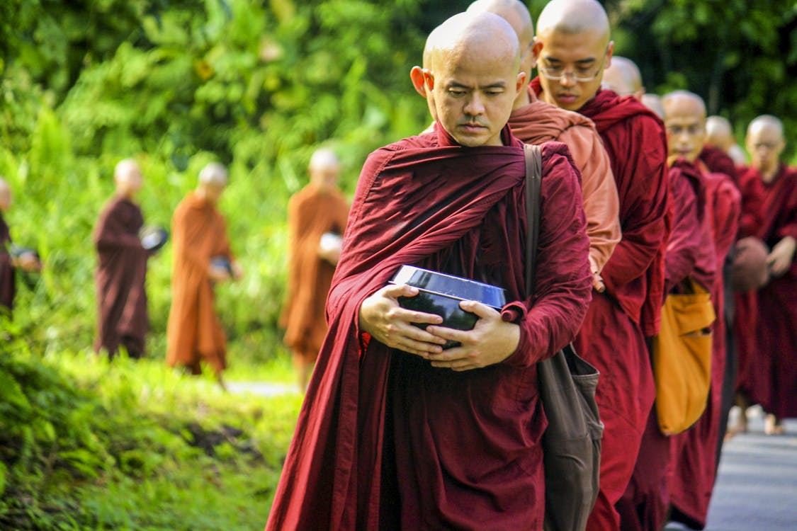 Monks Holding Jars Near Green Leafed Trees