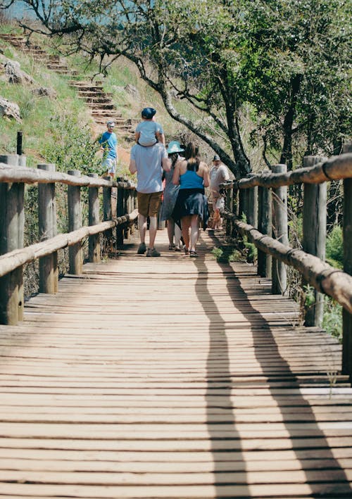 People walking on a wooden bridge over a river