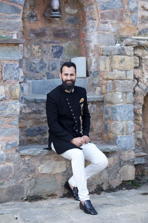 Free Man dressed in traditional attire poses on a stone bench in an urban setting. Stock Photo