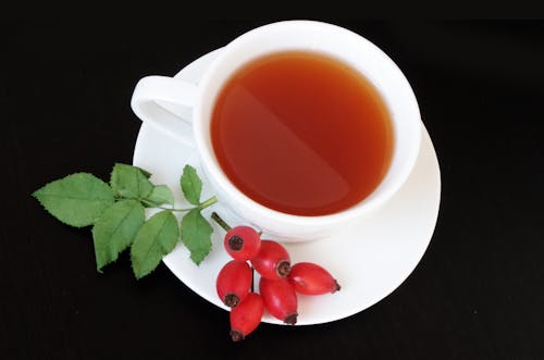 White Teacup With Red Fruits Beside