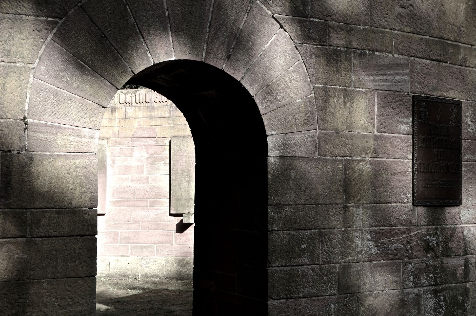 Rustic stone archway with dramatic shadows depicting historic architecture.
