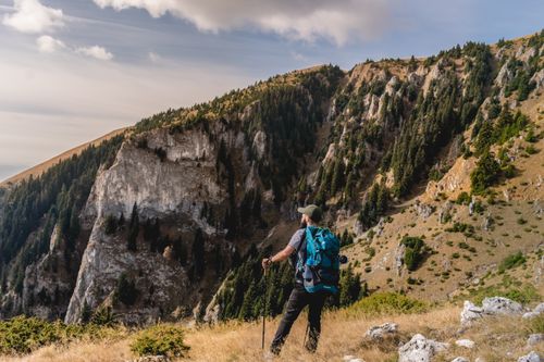 Free Man hiking in Romanian mountains, admiring scenic views and nature. Stock Photo