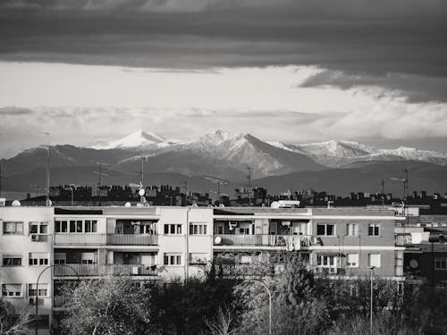 A black and white photo of a city with snow capped mountains