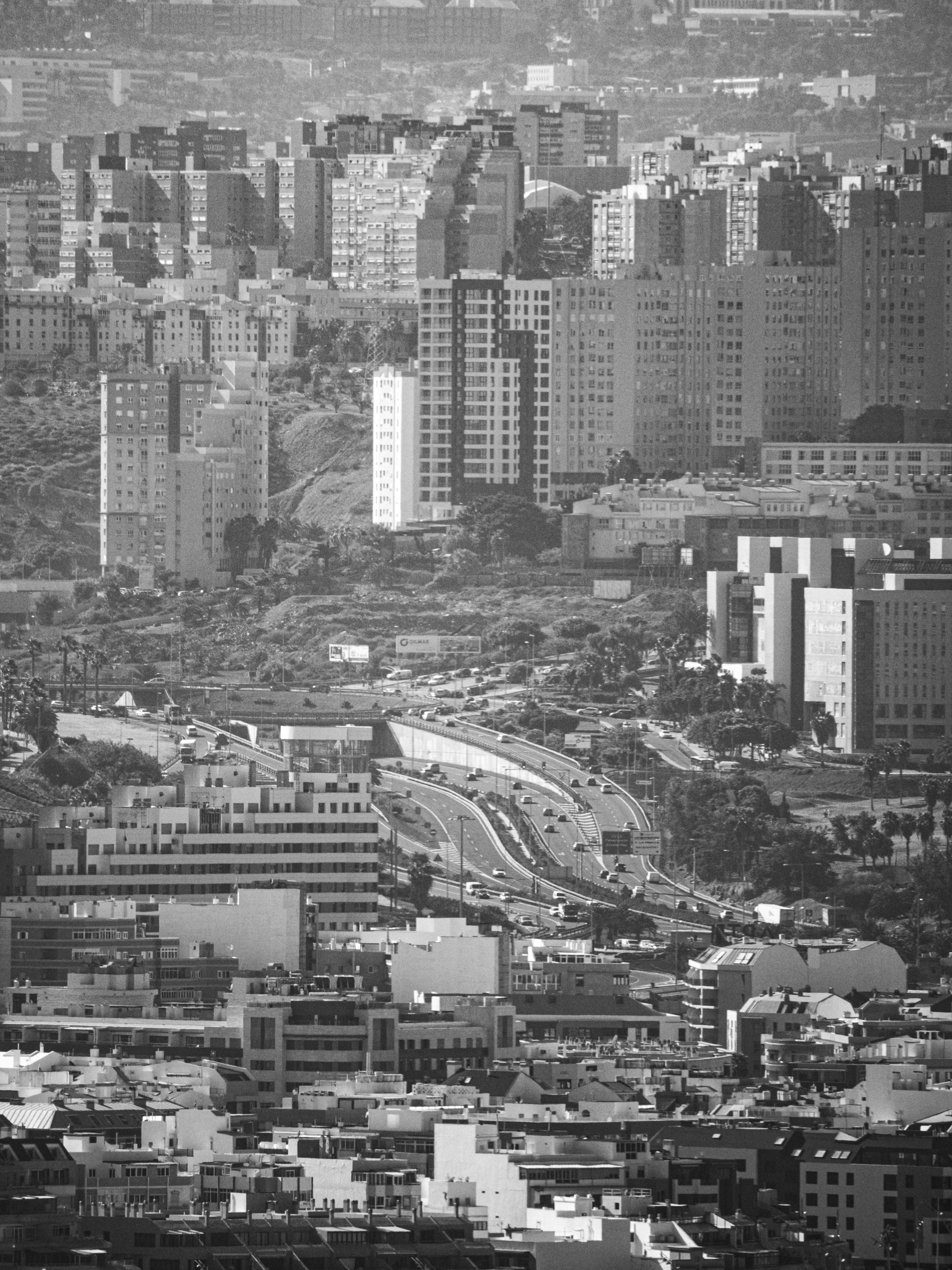 Black and white aerial view of Las Palmas cityscape featuring high-rise buildings and roadways.