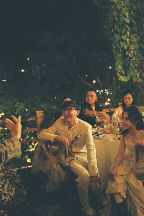 Invitados riendo genuinamente en una mesa durante la recepción de una boda de noche