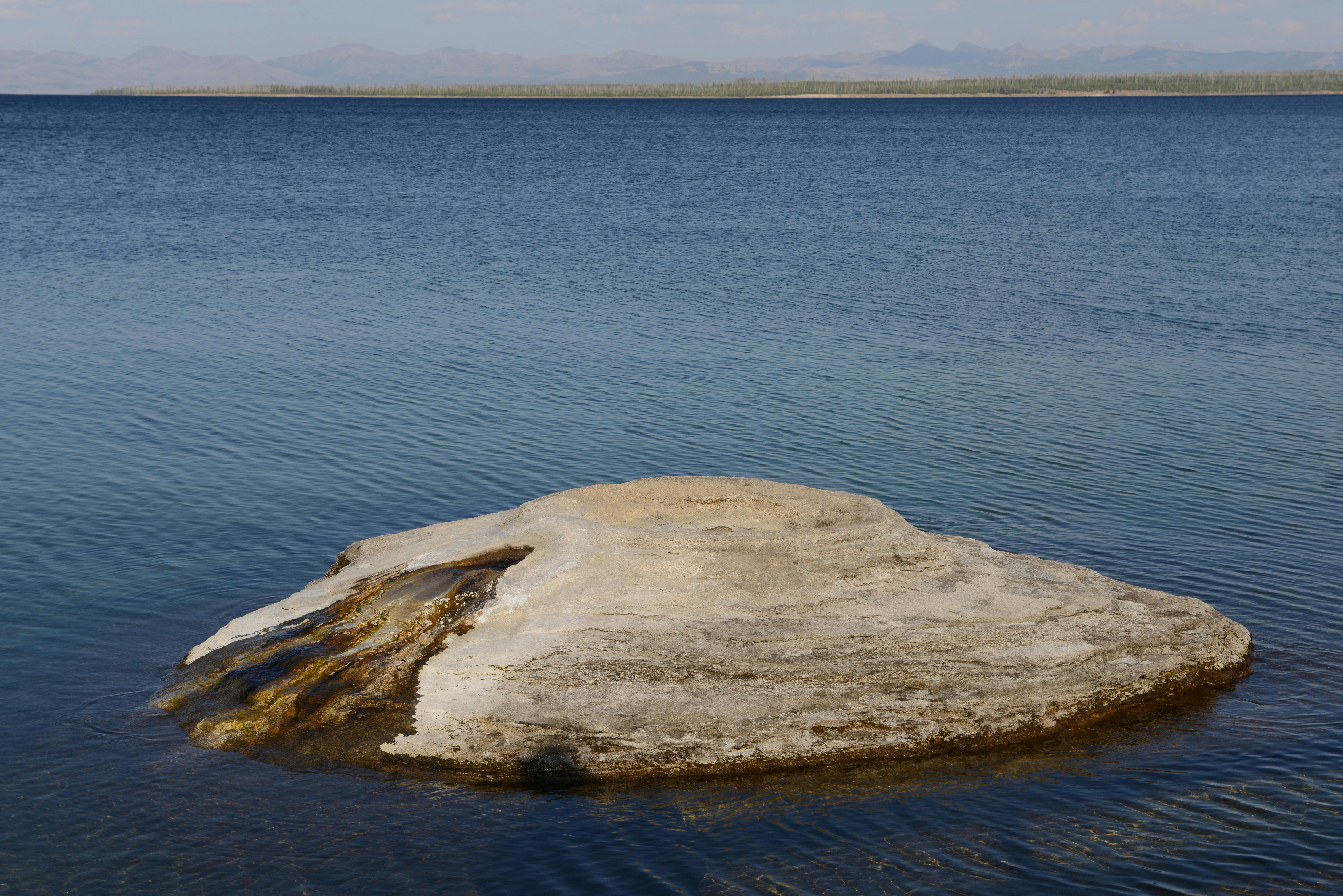 Geyser cone on Yellowstone Lake at Yellowstone National Park under clear skies.