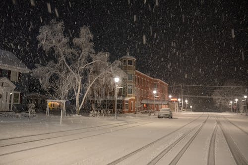 A snowy night scene with a train tracks and buildings